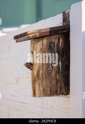 A birdhouse built from a tree trunk, a nesting box on a wall. Stock Photo