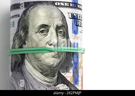 Rolled hundred dollar bills are tied with a green banker's rubber band. Portrait of Franklin gagged. Pay for silence, corruption Stock Photo