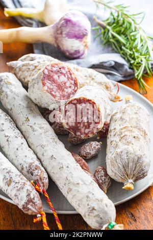 Traditional sausage with white mold. Dried pork salami on plate. Stock Photo