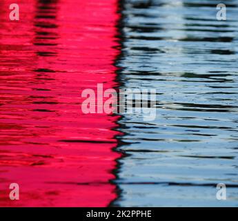 Shining blue and pink water in pool, surface with ripples on reflecting background Stock Photo