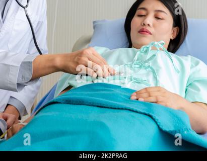 Male doctor examining female patient in hospital room. Stock Photo