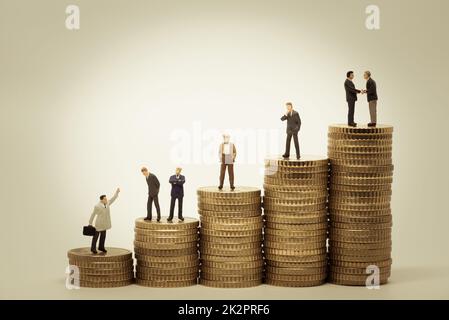Various people standing on stacks of coins Stock Photo
