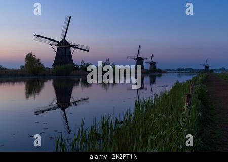 Traditional Dutch windmills with a colourful sky just before sunrise in Kinderdijk, The Netherlands Stock Photo