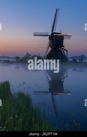 Traditional Dutch windmills with a colourful sky just before sunrise in Kinderdijk, The Netherlands Stock Photo