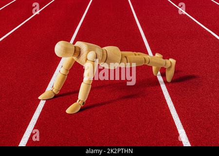 Wooden sportsman doing push ups on running track Stock Photo