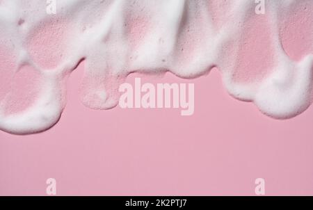 Texture of the foam of the skin care cleanser. Soap bubbles with copy space on pink background. Stock Photo