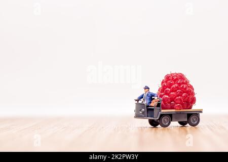 Miniature lorry loaded with giant raspberry. Fruit delivery concept Stock Photo