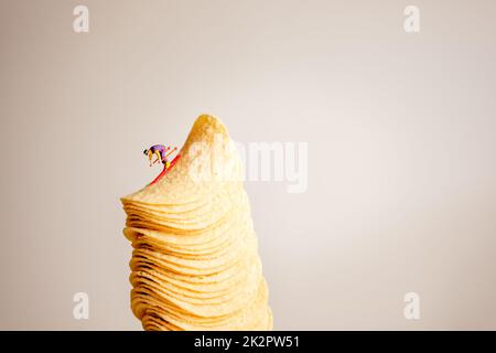 Miniature skier sliding down the stack of potato chips Stock Photo