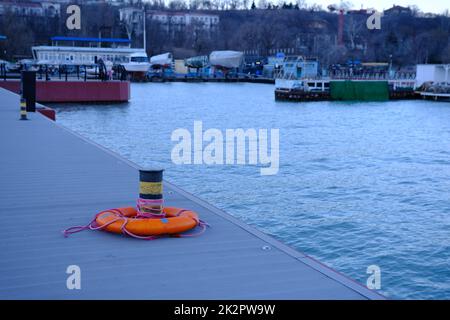 Lifebuoy ring on berth near the bollard with sea view of Marina outdoors Stock Photo