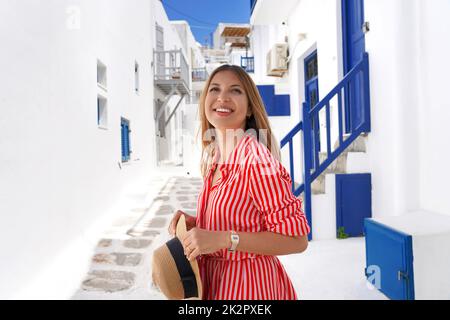 Portrait of fashion traveler girl looking up visiting Mykonos traditional whitewashed village in Greece Stock Photo