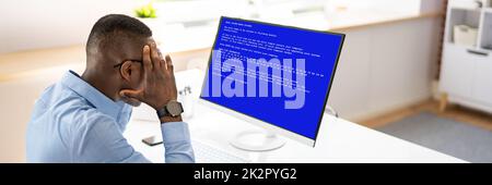 Worried Man At Computer With System Failure On The Screen Stock Photo