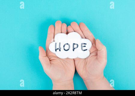 Holding a cloud with the word hope in the palm of the hands, trust and believe concept, having faith in the future, hopeful positive mindset Stock Photo
