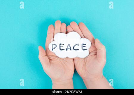 Holding a cloud with the word peace in the hands, stop war, support, living peaceful together Stock Photo