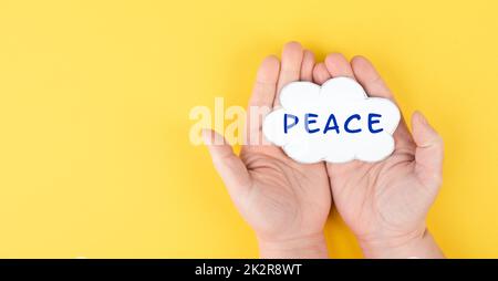 Holding a cloud with the word peace in the hands, stop war, support Ukraine, living peaceful together, color of ukrainian flag Stock Photo