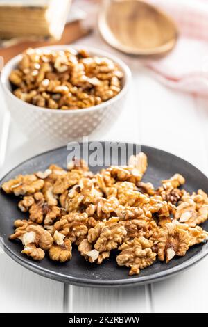 Peeled walnut kernels on plate on white table. Stock Photo