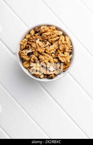 Peeled walnut kernels in bowl on white table. Stock Photo