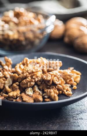 Peeled walnut kernels on plate on black table. Stock Photo