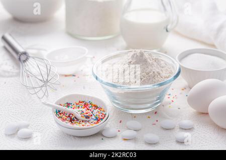 Baking background with flour, eggs, sugar sprinkles, kitchen tools, utensils Stock Photo