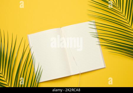 open notebook with blank white sheets on a yellow background, top view. Stock Photo