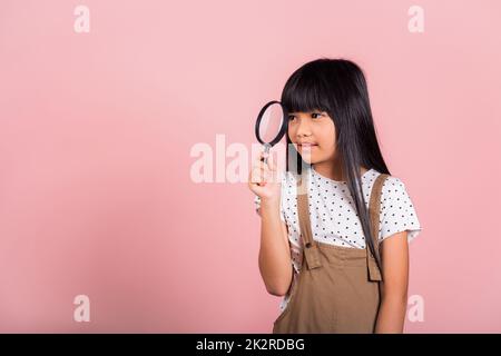 Asian little kid 10 years old funny looking through magnifying glass Stock Photo