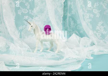 a shiny white unicorn carrying a plastic skull on its back Stock Photo