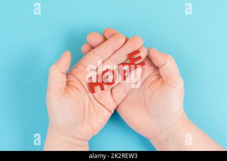 Holding the word hope in the palm of the hands, trust and believe concept, having faith in the future, hopeful positive mindset Stock Photo