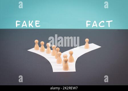 Crowd of people follow the path to the fake information, one thinks different and takes his own way and decisions, propaganda and conspiracy theory concept, media and manipulation issue Stock Photo