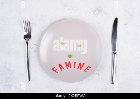 Famine is standing in german language on the plate, food shortage and starving because of the war and inflation, political issue Stock Photo