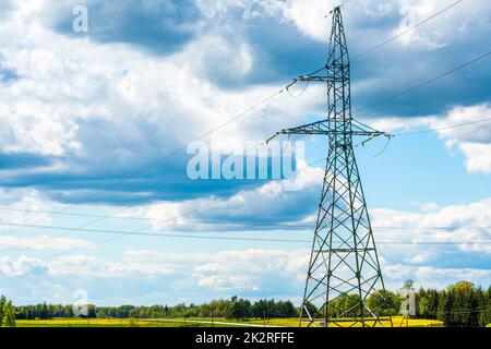 Power transmission lines and tall electricity pylon against the blue sky in the countryside Stock Photo