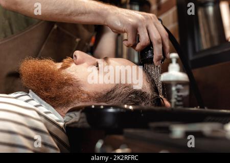 Barber and bearded man in barber shop Stock Photo