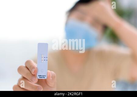 woman holding Rapid Antigen Test kit with Positive result during swab COVID-19 testing Stock Photo