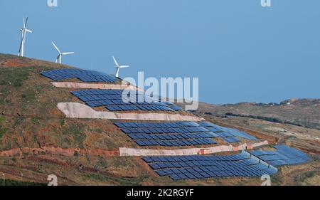 photovoltaics solar panels and wind turbines generating electricity on hill and blue sky. Ecology green nature concept. Stock Photo
