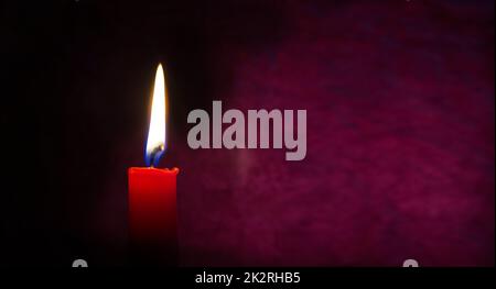 Red candle burning in the dark red background Stock Photo