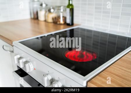 Stove and cooker red hot. Induction, ceramic cooktop, electric stovetop and hob in kitchen. Warm plate ready for cooking. Contemporary interior design. Stock Photo
