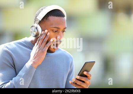 Shocked man with headphones and phone in the street Stock Photo
