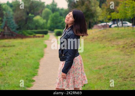 young pretty brunette woman with beautiful long hair in the park Stock Photo