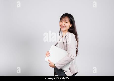 Side view woman smiling confident smiling holding closed laptop Stock Photo