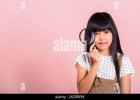 Asian little kid 10 years old funny looking through magnifying glass Stock Photo