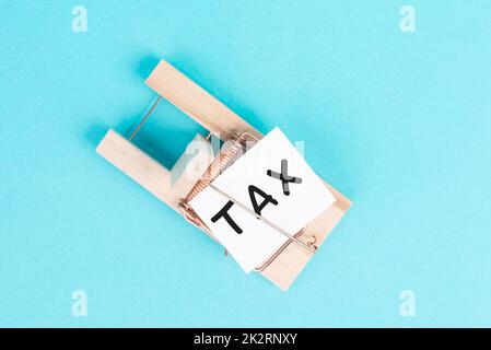 Paper with the word tax in a mousetrap, high financial burden, costs and expenses in business, taxation by the state Stock Photo