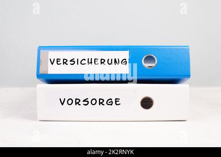 Two folders with the words insurance and precaution in german langauge, documents at an office, risk protection, financially security Stock Photo
