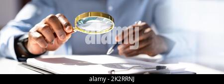 Human Hand Holding Magnifying Glass Over Invoice Stock Photo