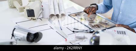 Person Watching Footage On Tablet With Security Equipment Stock Photo