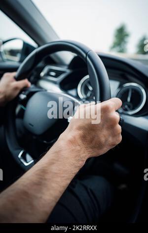 Male hands on a car's steering wheel Stock Photo