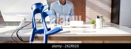 Crutches Leaning On Table In Front Of Injured Patient Stock Photo