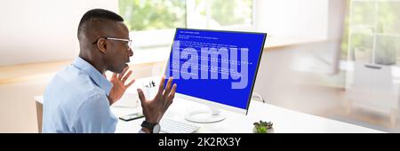 Worried Man At Computer With System Failure On The Screen Stock Photo