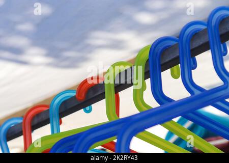 Numerous colourful plastic clothes hangers on a clothes rail Stock Photo
