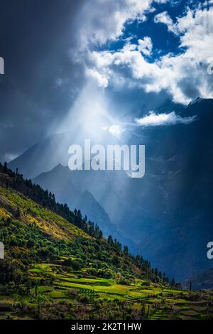 Sun rays through clouds in Himalayan valley in Himalayas Stock Photo