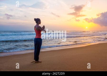 Woman doing yoga on beach Stock Photo