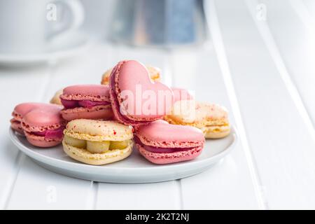 Heart shaped Sweet macarons on plate on white table. Stock Photo