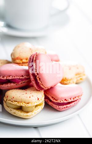 Heart shaped Sweet macarons on plate on white table. Stock Photo